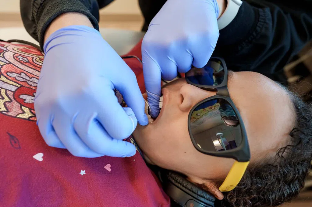 Young girl getting teeth flossed