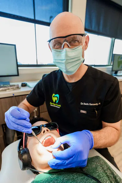 dentist smiling with mask on working on patient